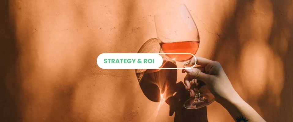 Hand raising a glass of rosé wine against a sunlit orange wall, with the label “Strategy & ROI”