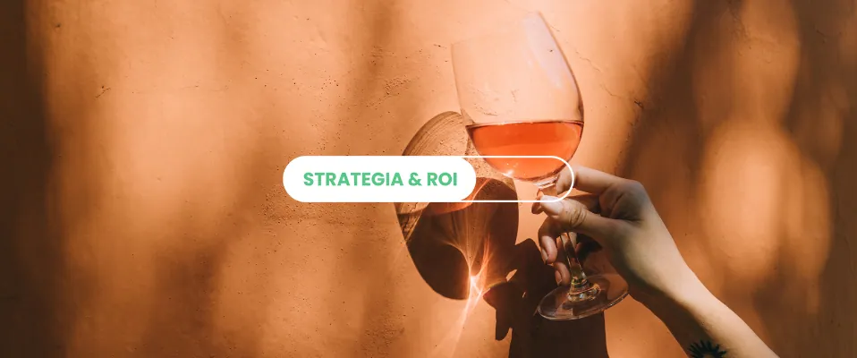 Mano che solleva un calice di vino rosato contro un muro arancione illuminato dal sole, con l'etichetta «Strategia & ROI»