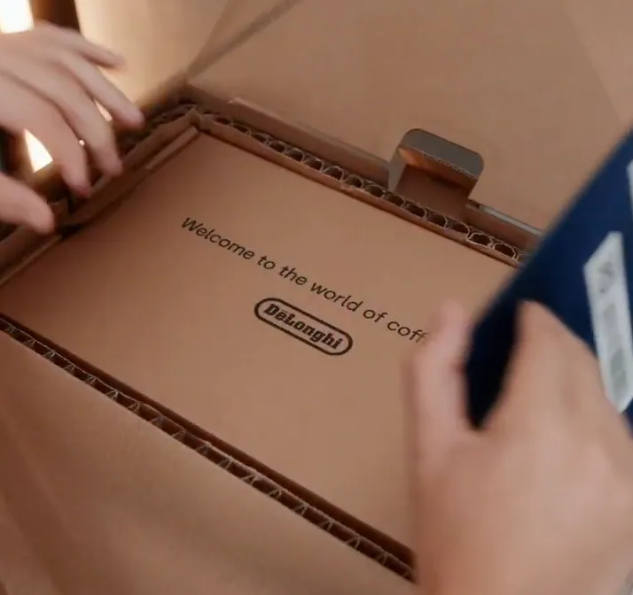 Mani che aprono una scatola De'Longhi con la scritta Welcome to the world of coffee
