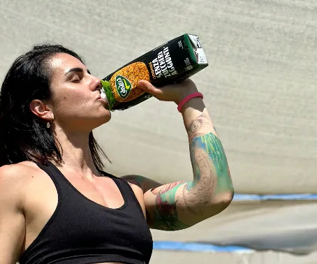 Una creator fitness beve da una bottiglia di succo Todis dopo l’allenamento