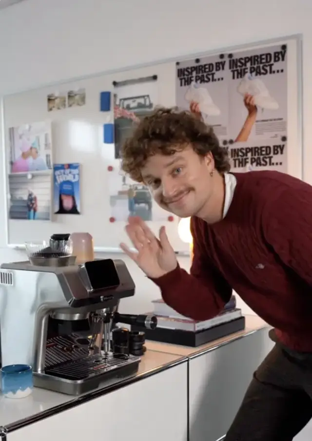 Creator next to an espresso machine in an office